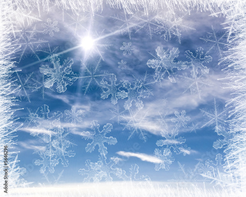 Cold background frame with blue sky and snow flakes.