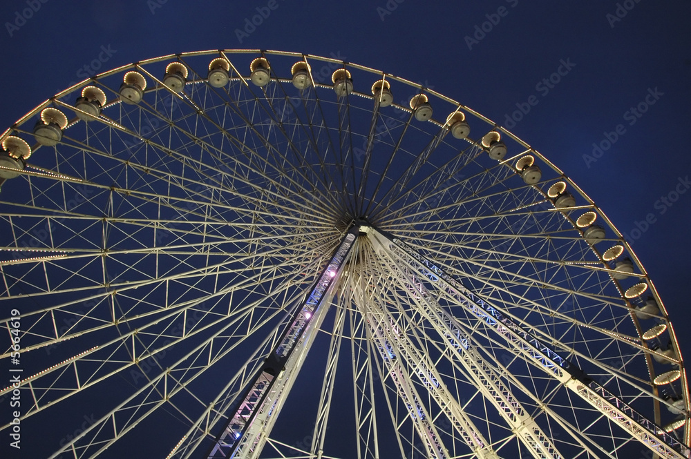 Giant ferris wheel with lights against a dark blue night sky