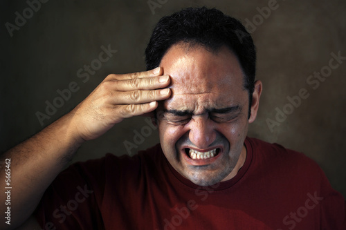 Portrait of a man in painfull expression with a headhache.