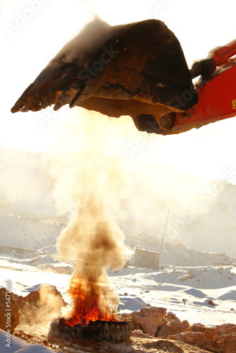 Ladle of a loader heat above a burning tire cover