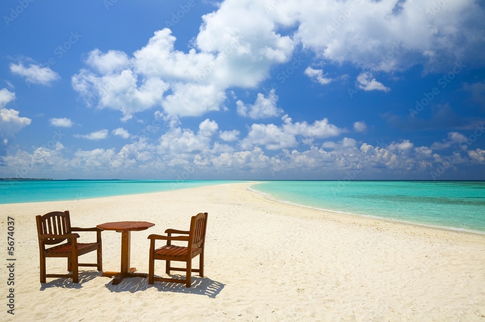 Two chairs and one table are on the coral sandy beach, Maldives