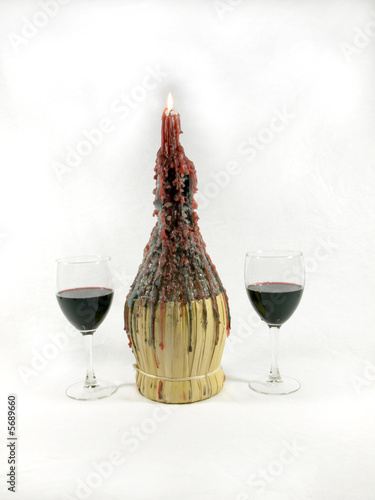 Photo of 2 glasses of wine nest to a wine bottle candle holder