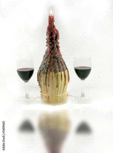Photo of two glasses of wine next to a wine bottle candle holder