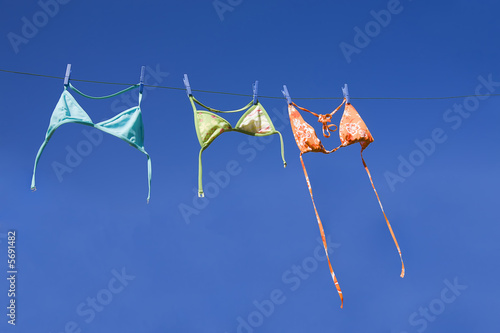 Three colorful bikini tops drying on washing line