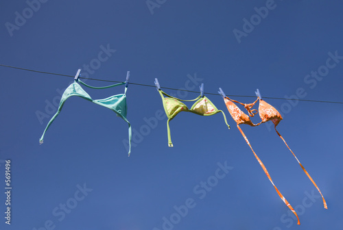 Three colorful bikini tops drying on washing line 