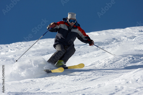 freeride skiing in powder snow against blue sky