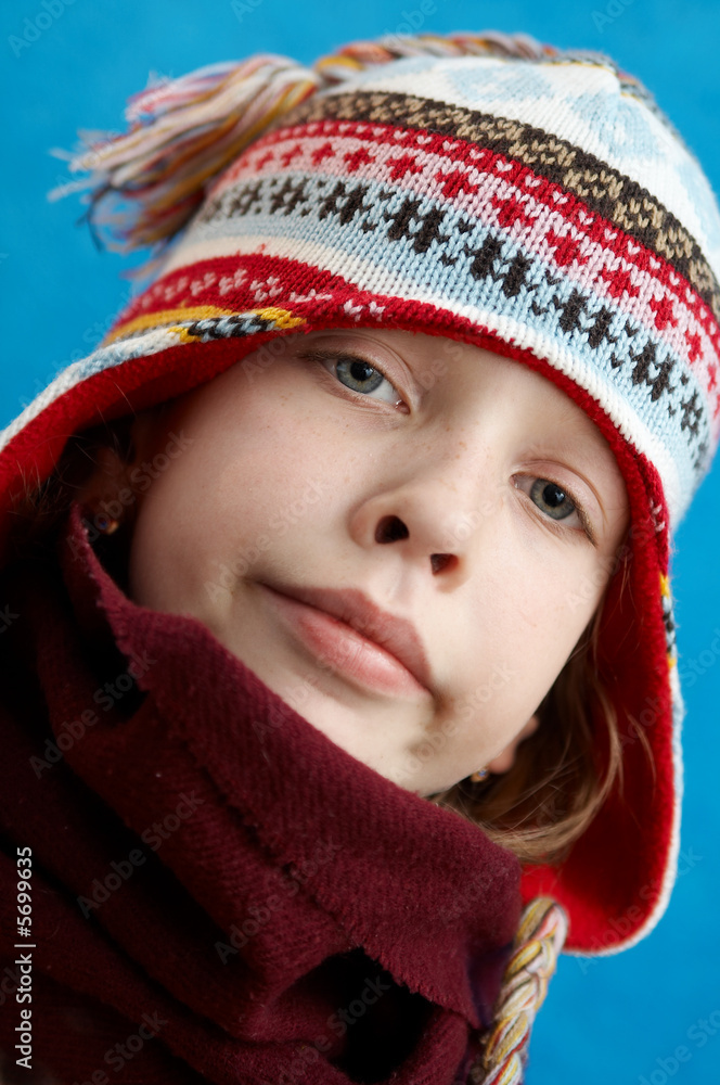 Young girl wearing woolen cap, scarf and gloves on blue Young girl wearing woolen cap, scarf and gloves on blue