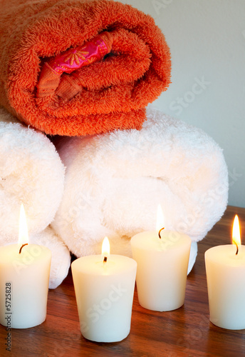 Relaxing spa scene with white and orange rolled up towels 