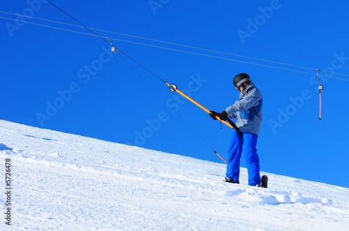 snowboarder on skilift in winter ski resort blue sky