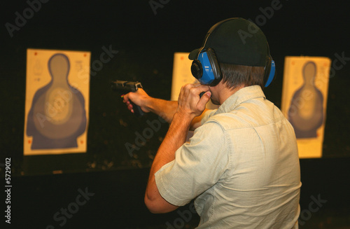 marksman on the range using a flashlight while shooting a pistol photo
