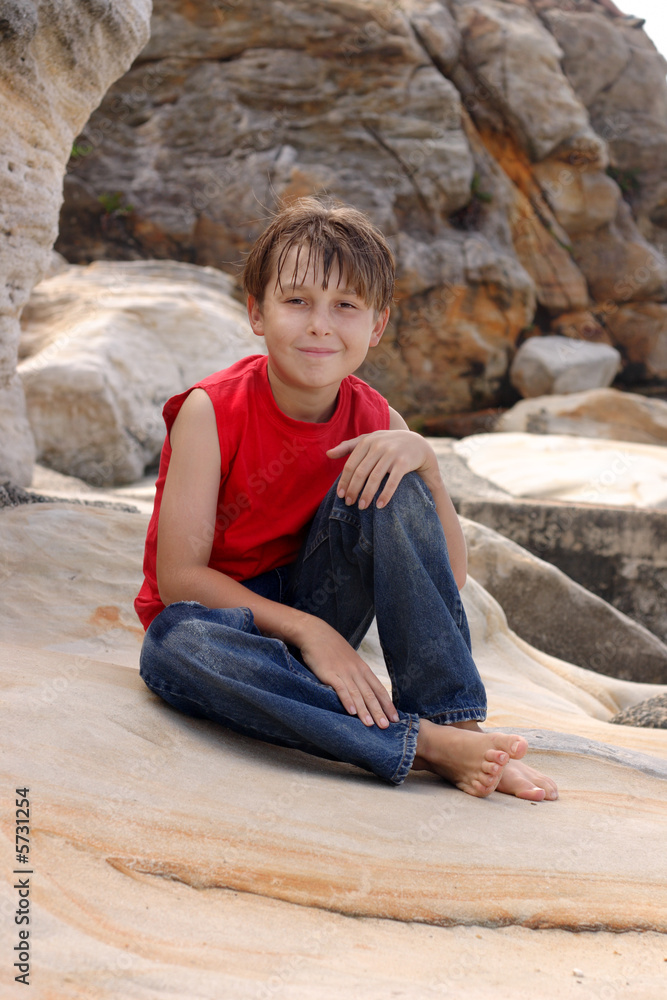 A happy young boy relaxing on some sandstone rocks A happy young boy relaxing on some sandstone rocks