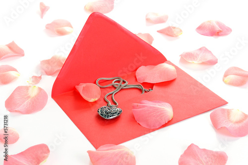 Love letter with heart-shaped necklet and pink rose petals