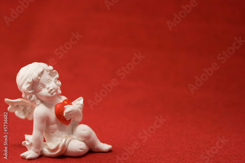 The white cupid with heart on a red background