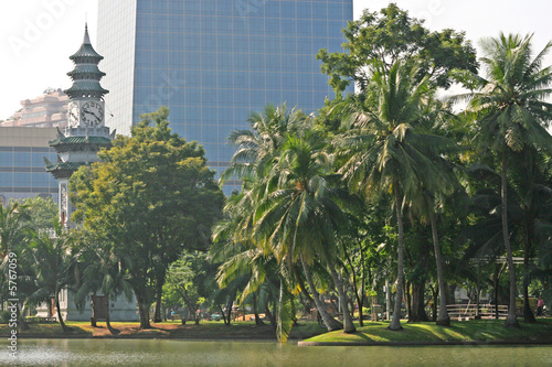 Tropical trees and clock tower in Lumpini Park, Bangkok