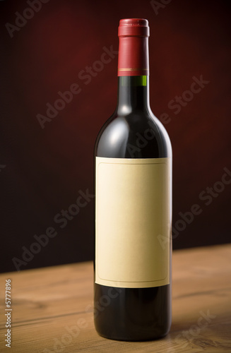 Red wine bottle on wooden table over dark red background
