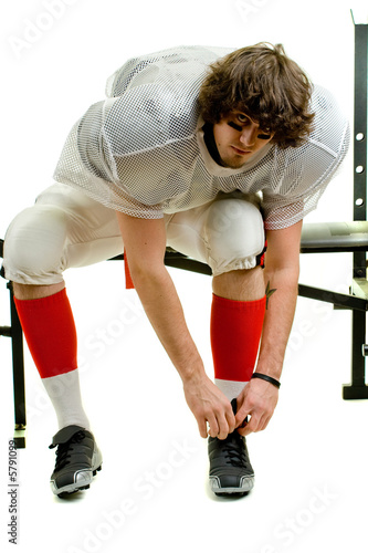 American football player. Tying shoe on weight bench. © Nicholas Piccillo