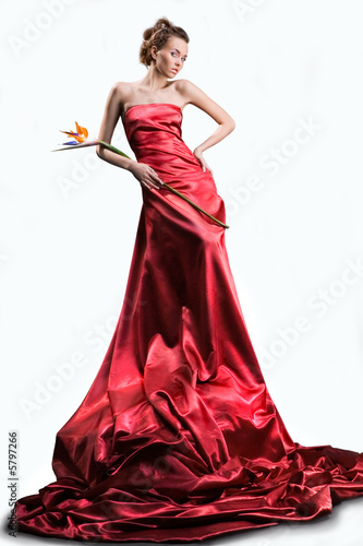 beautiful girl in a long red dress holds an flower in a hand