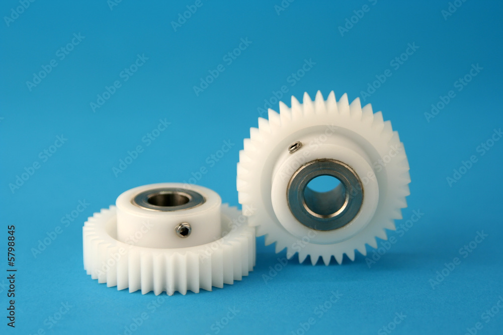 Two white cogwheels on blue background signifying teamwork Two white cogwheels on blue background signifying teamwork