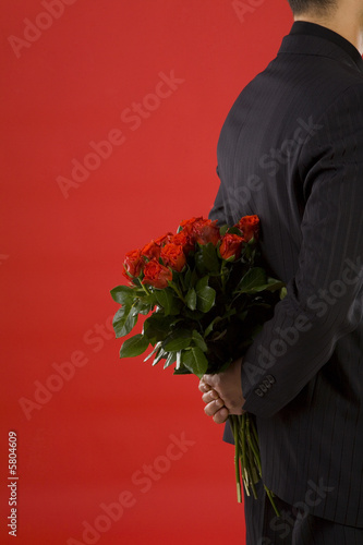 Businessman holding bouquet of roses behind his back