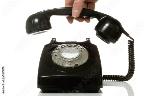 Foto Retro black telephone being picked up.