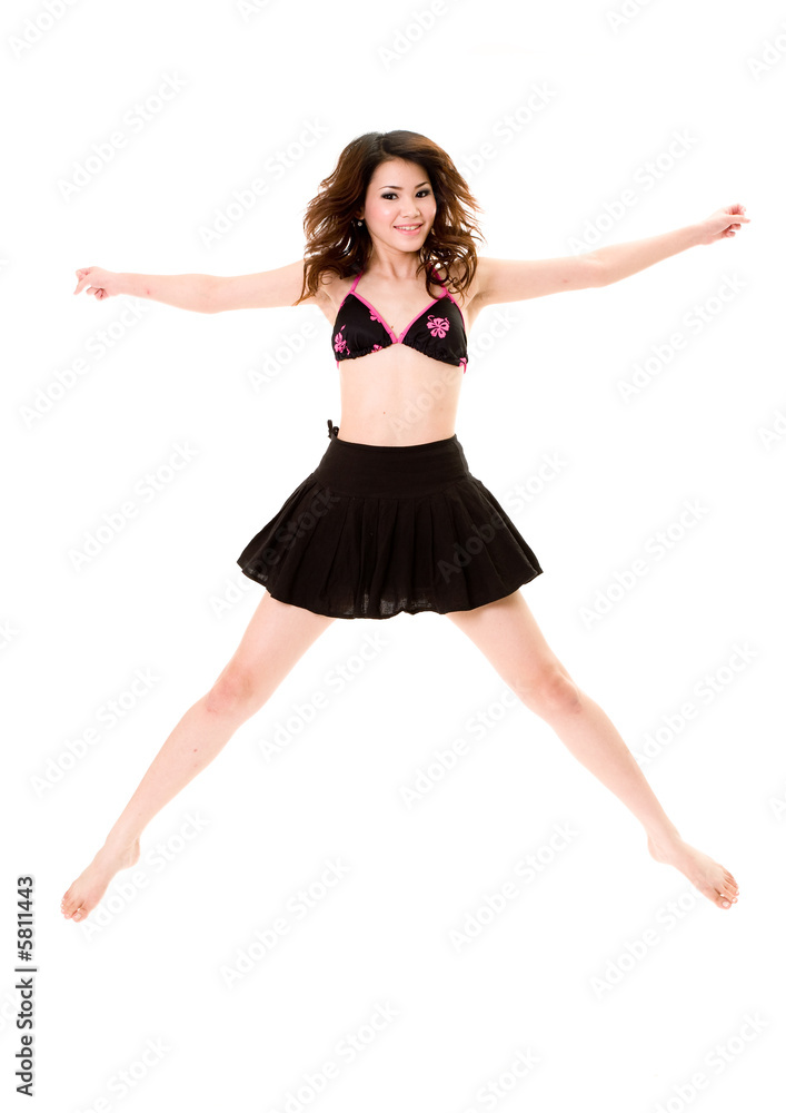 young woman in bkini top & skirt jumping freely and happily young woman in bkini top & skirt jumping freely and happily