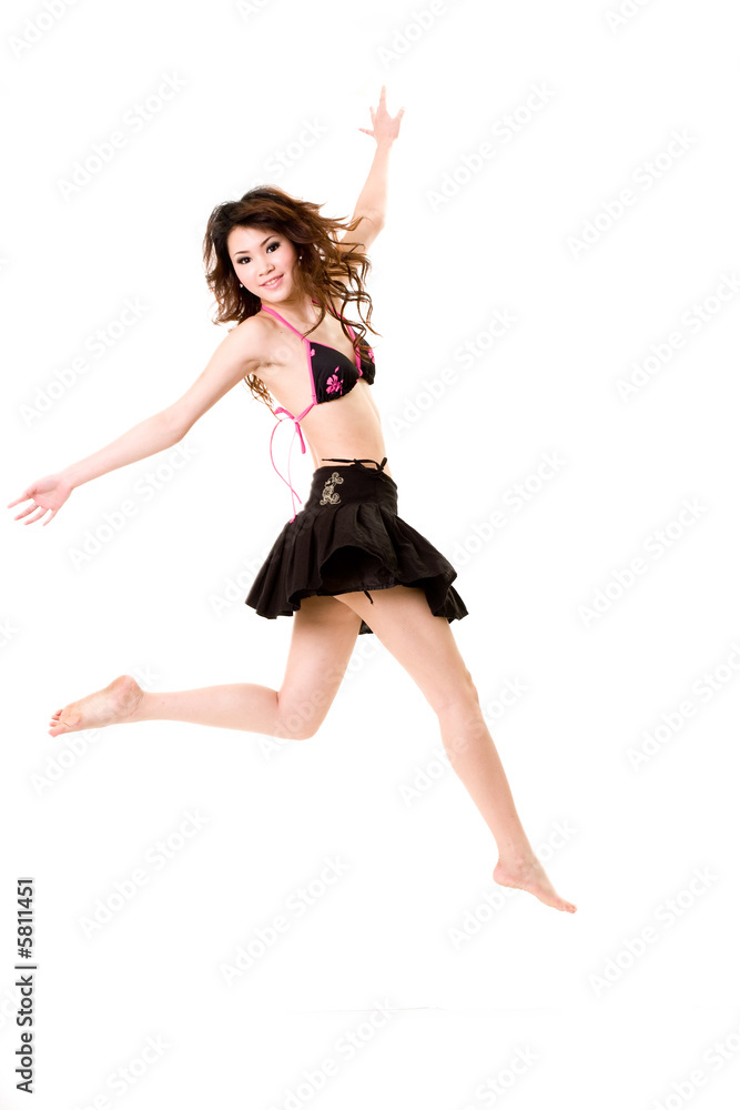 young woman in bkini top & skirt jumping freely and happily