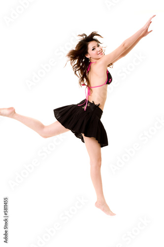 young woman in bkini top & skirt jumping freely and happily