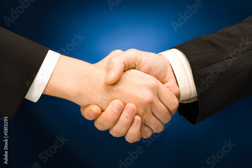 Business handshake - making a deal over blue background