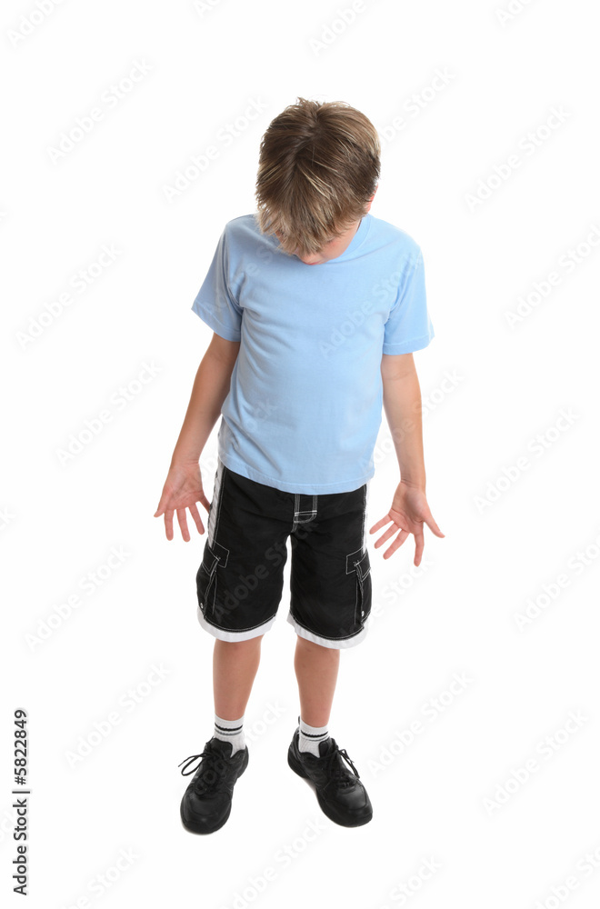 Boy standing in plain blue t-shirt and shorts looking down. Boy standing in plain blue t-shirt and shorts looking down.