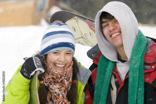 A lifestyle image of two young adult (age 18-20) snowboarders