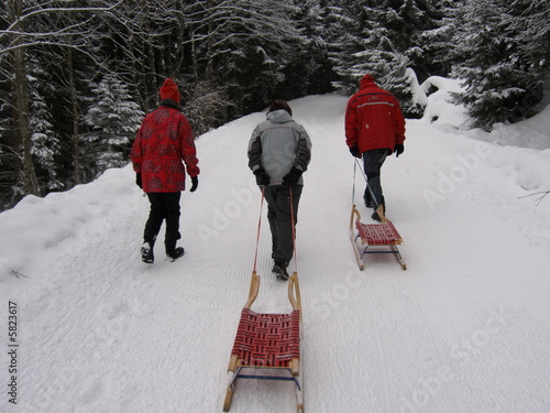 Drei menschen auf rodelweg in verschneiter winterlandschaft 