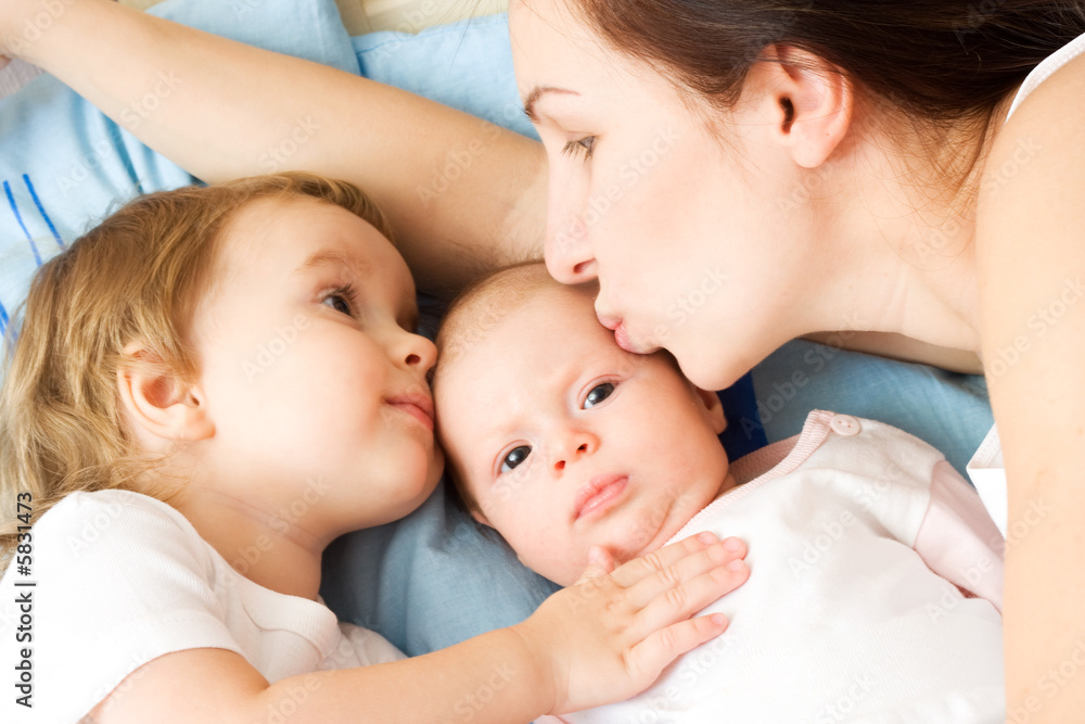 Happy mother with two daughters, kissing and holding them Happy mother with two daughters, kissing and holding them