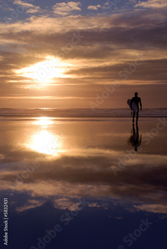 Surfer and cloud reflection at sunset.