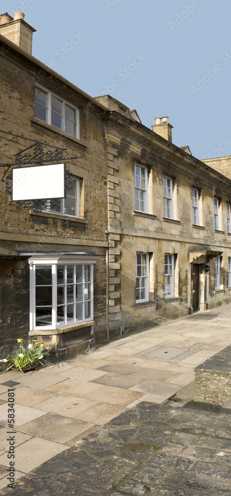 A row of old stone houses with a blank white sign.