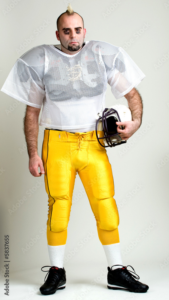 An American football player. Standing, holding helmet. An American football player. Standing, holding helmet.