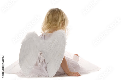 little girl wearily sitting in white dress and angel wings