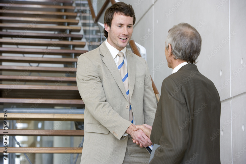 Two businessmen shaking hands on a staircase