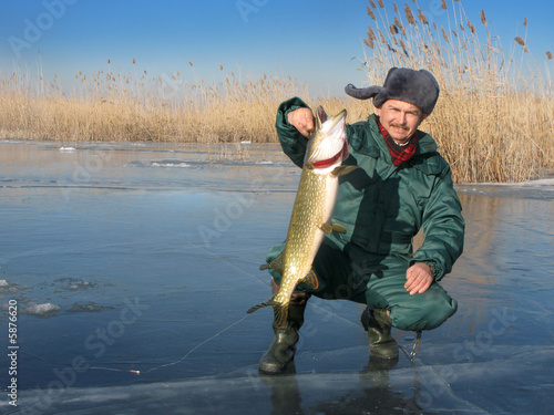 Russian fisher on ice with catched pike