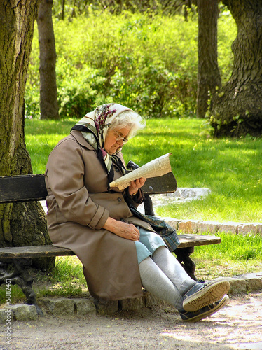 grandmother sits in spring  in a park on a bench