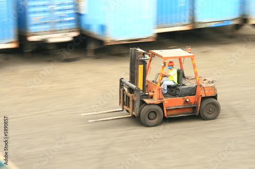 orange forklift in motion at a  ship port