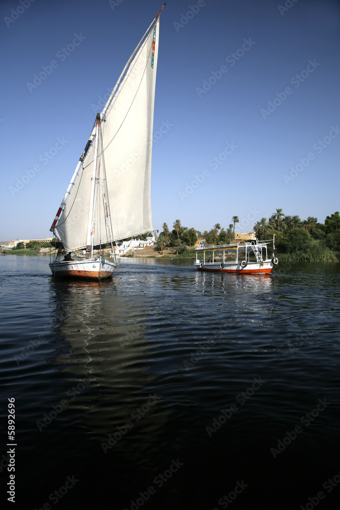 Obraz premium a sailboat and a motorboat in nile next luxor