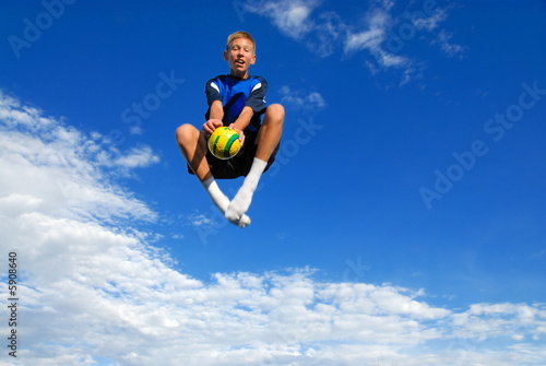 Boy jumping high with ball