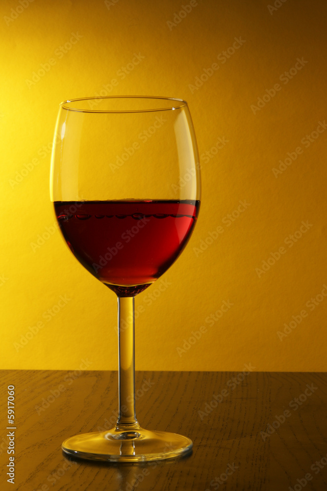 Single glass of red wine over yellow background