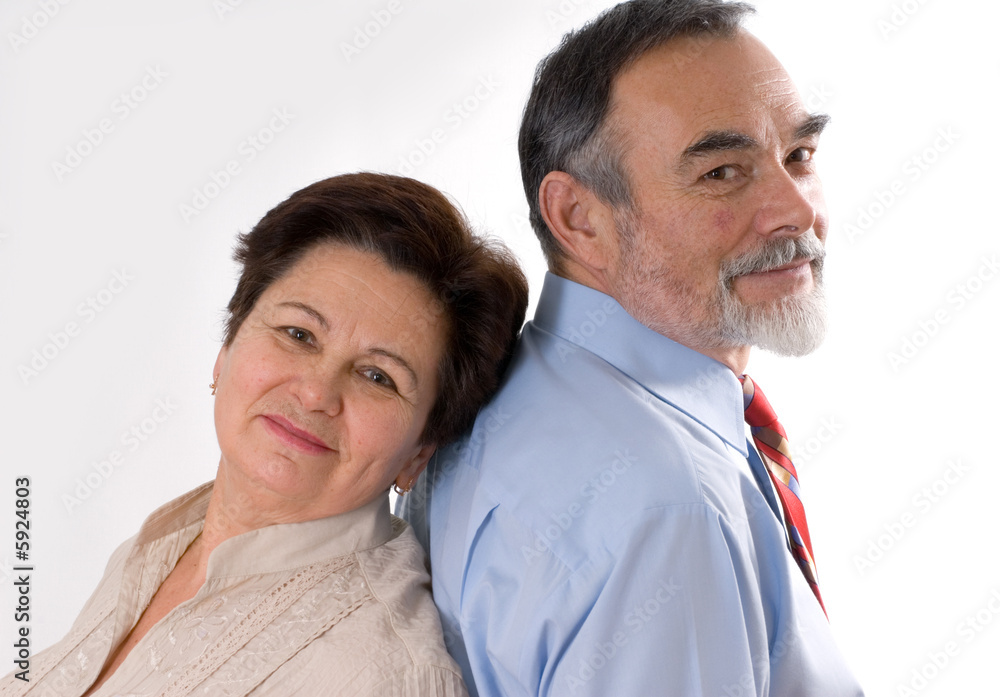 Cheerful elderly couple standing back to back Cheerful elderly couple standing back to back