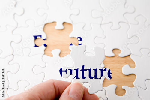 Hand holding a piece to complete puzzle with the word 