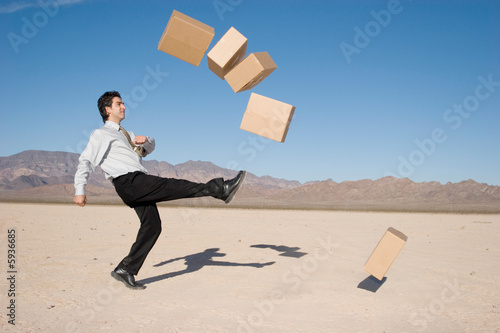 Businessman kicking boxes in the air