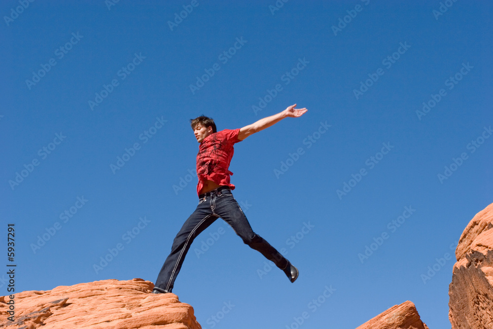 Obraz premium Handsome young man jumping on red rocks