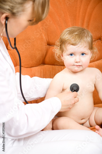 Doctor pediatrician examines little child using stethoscope
