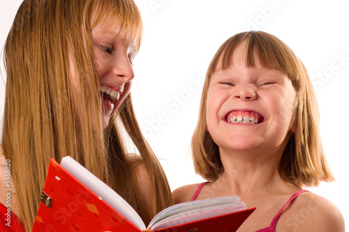 Two little girls holding red book, laughing,  on white