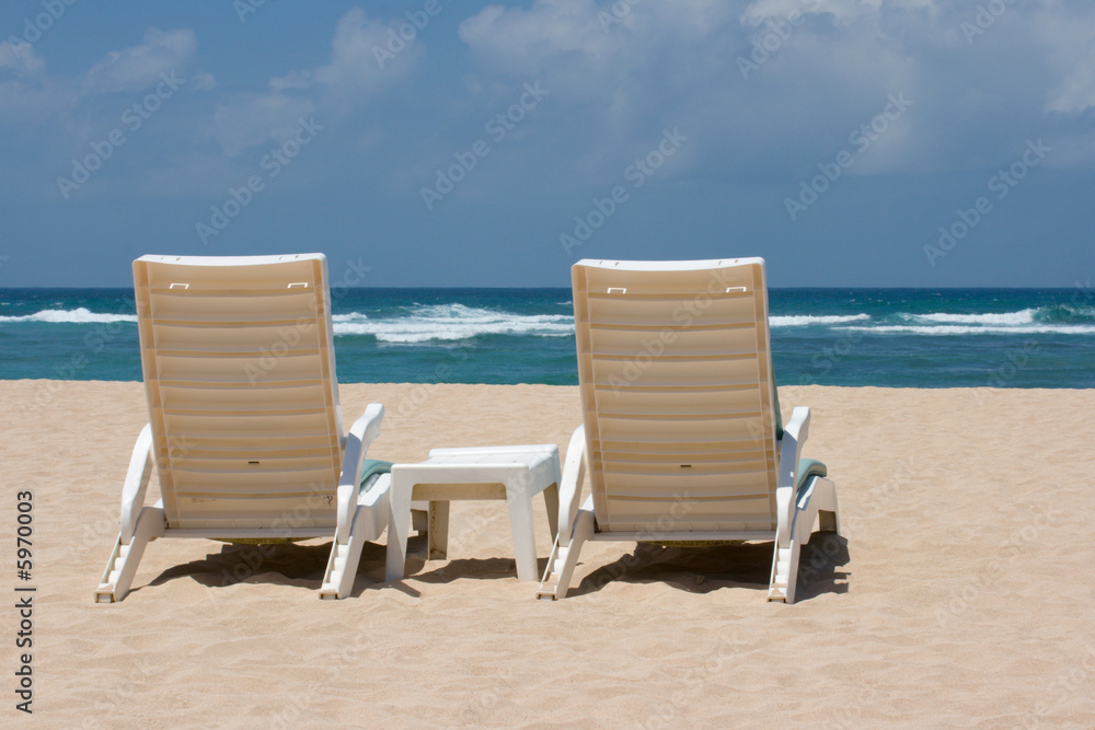 Two sun beach chairs on shore near ocean